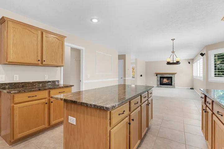 Kitchen featuring light wood cabinetry, stone countertops, and tile flooring