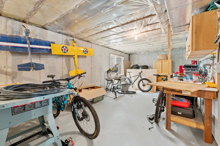 Unfinished basement space with concrete walls, exposed ceiling insulation, and a single light fixture