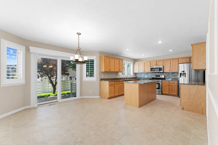 Kitchen featuring wood cabinetry, stainless steel appliances, a center island, and tile flooring