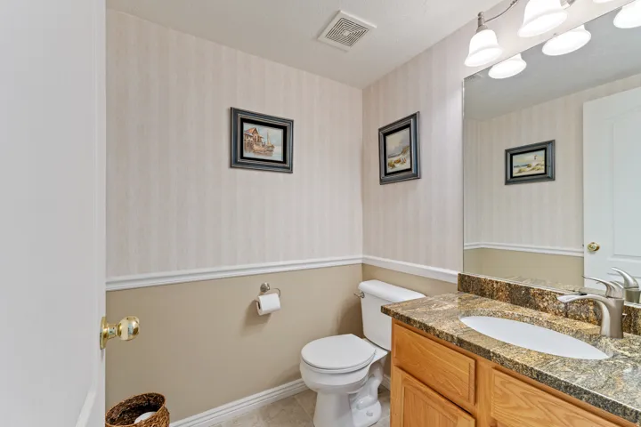 Vanity with integrated sink, stone countertop, wood-finish cabinetry, and wall-mounted mirror