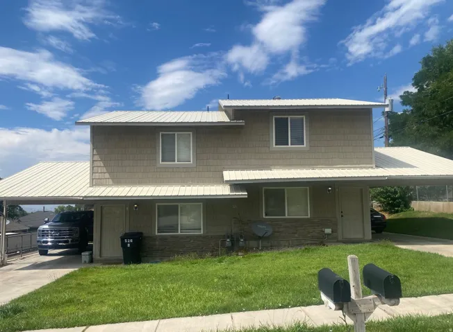 Two-story duplex with metal roofing, covered parking, and shake-style siding