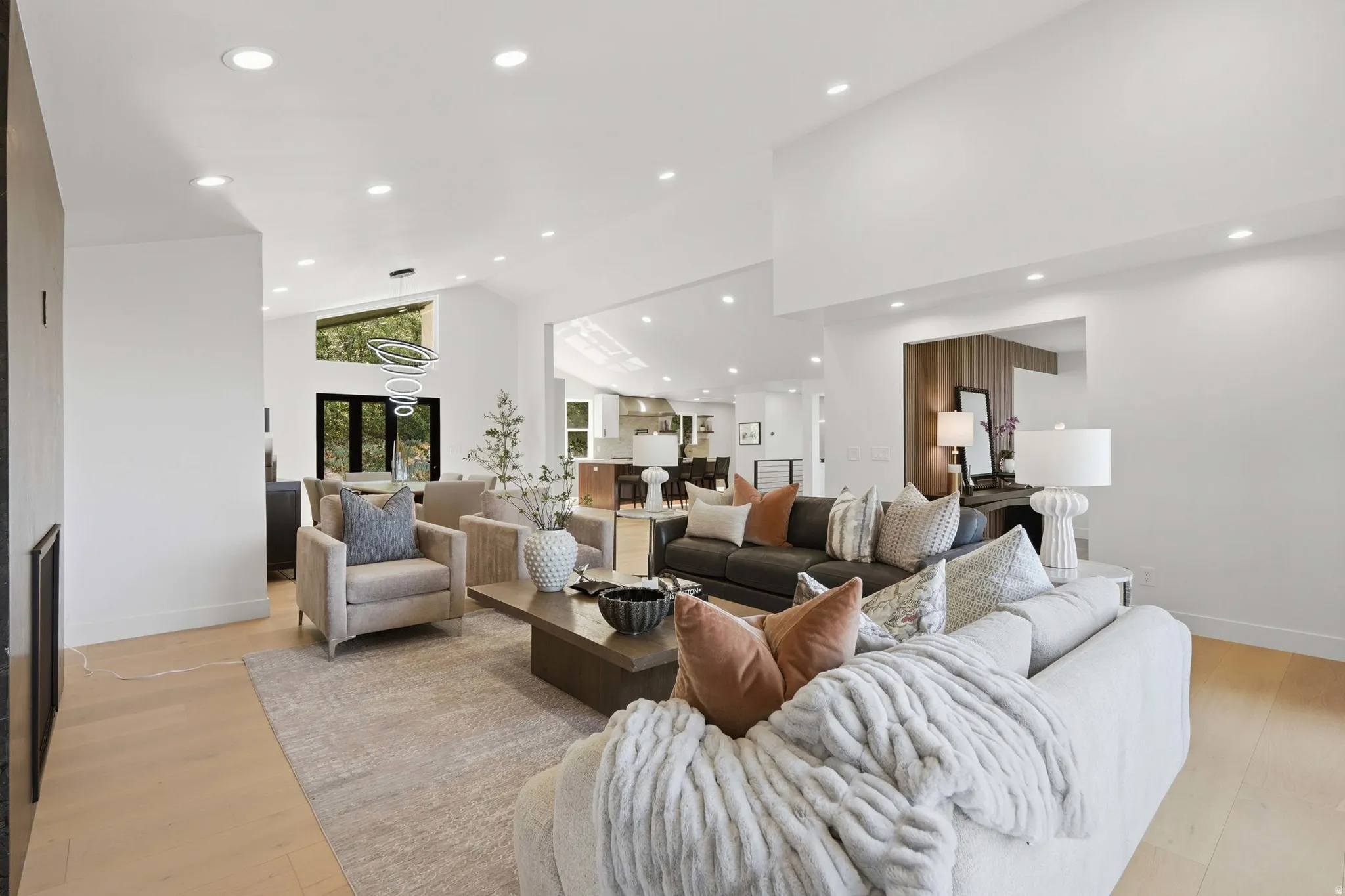 Spacious living area featuring high vaulted ceilings, recessed lighting, wood-finish flooring, and a modern chandelier