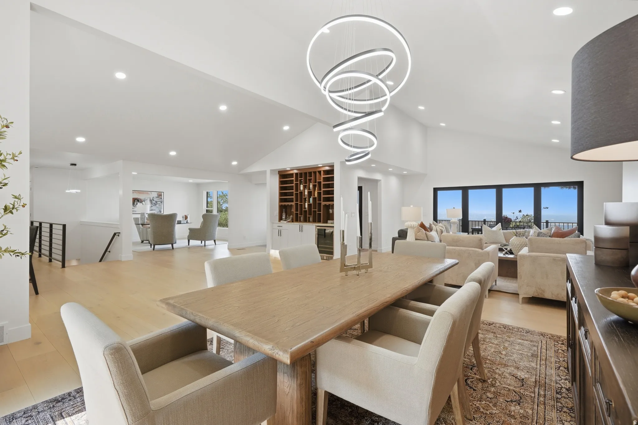 Vaulted ceilings, recessed lighting, wood-finish flooring, built-in wine storage, and a multi-pane glass wall