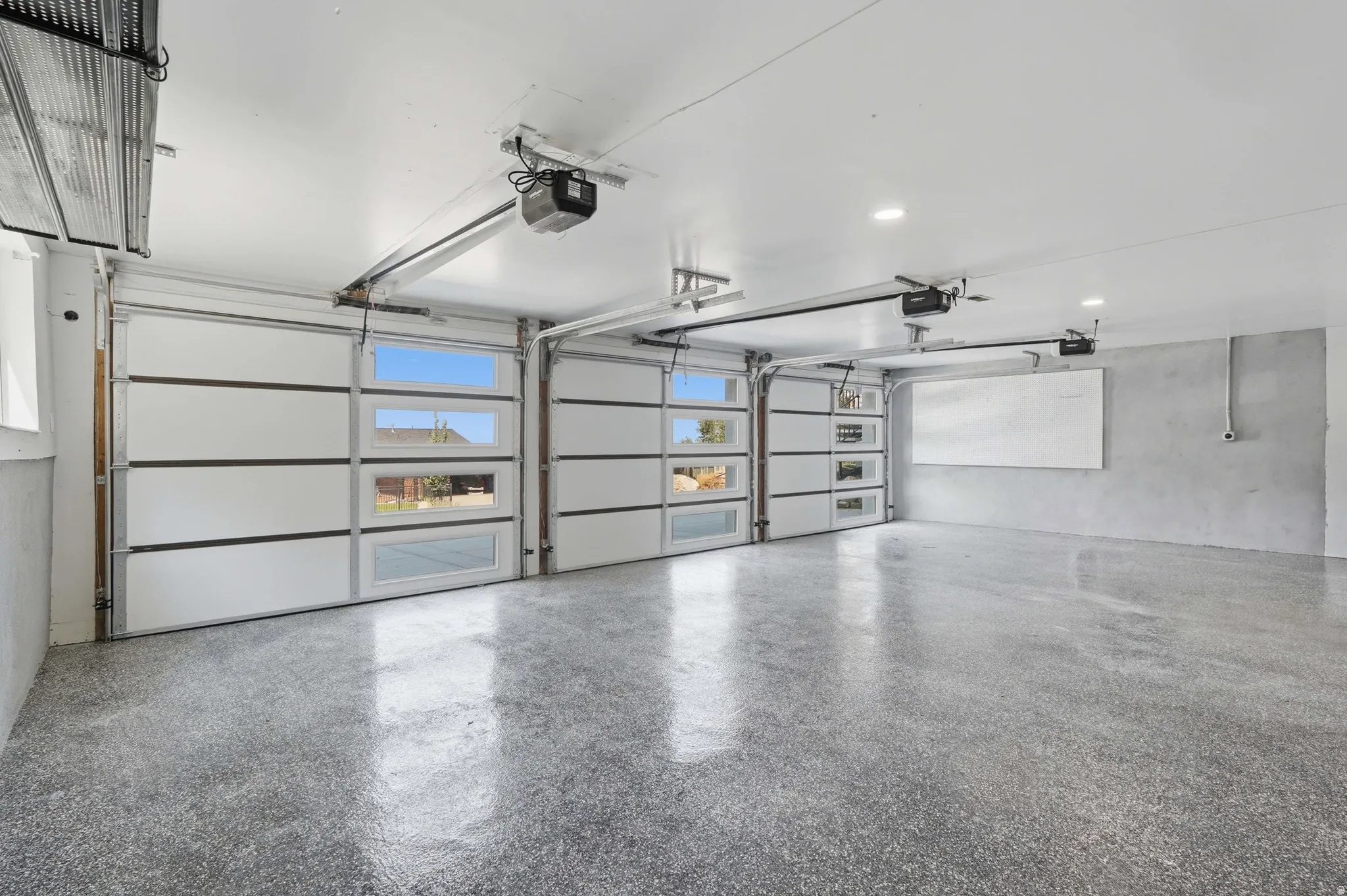 Two-car garage featuring segmented overhead doors with clear panels, automatic door openers, recessed lighting, and an epoxy-coated concrete floor