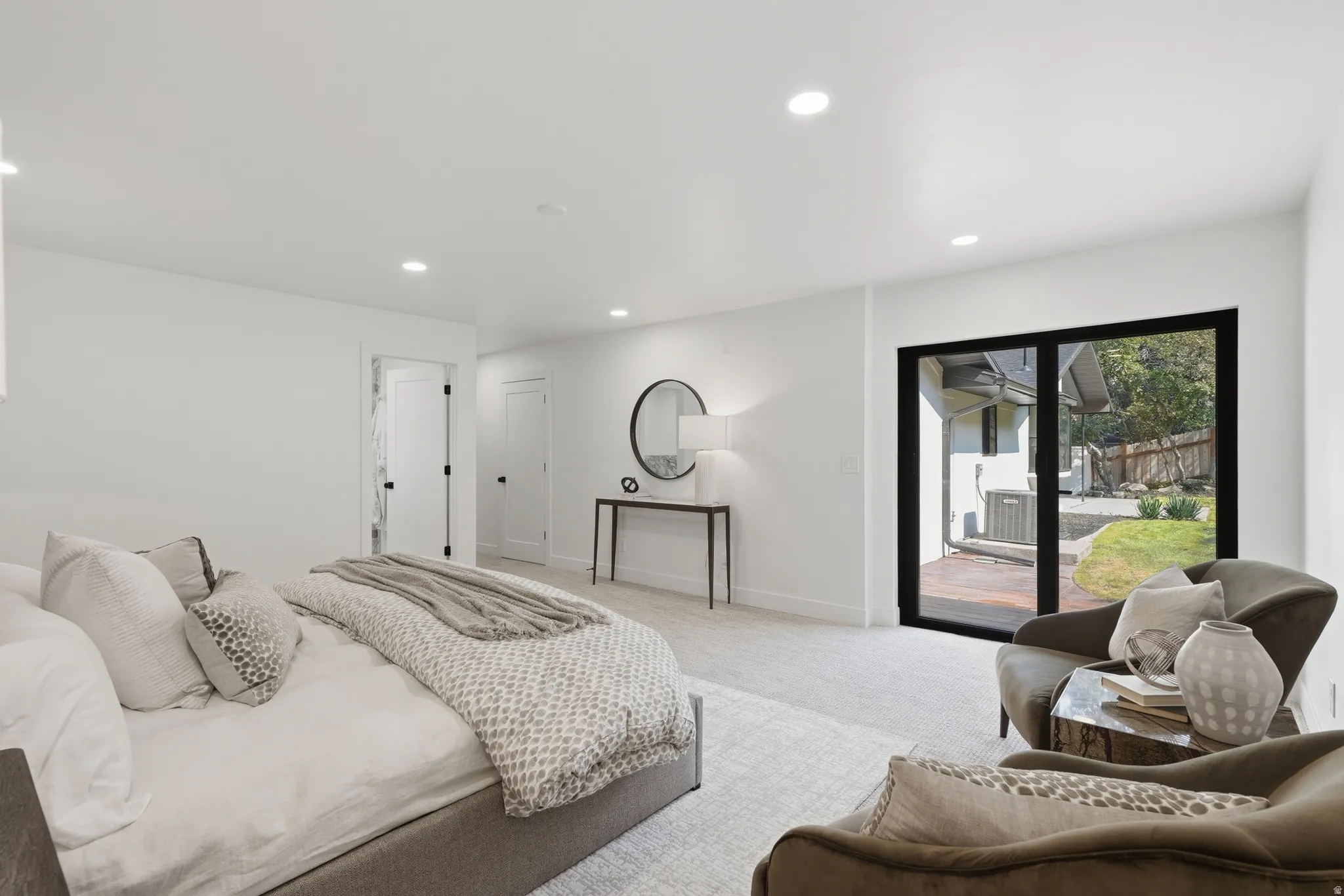Recessed lighting, light-toned carpeting, white walls, and a large black-framed sliding glass door opening to an outdoor patio