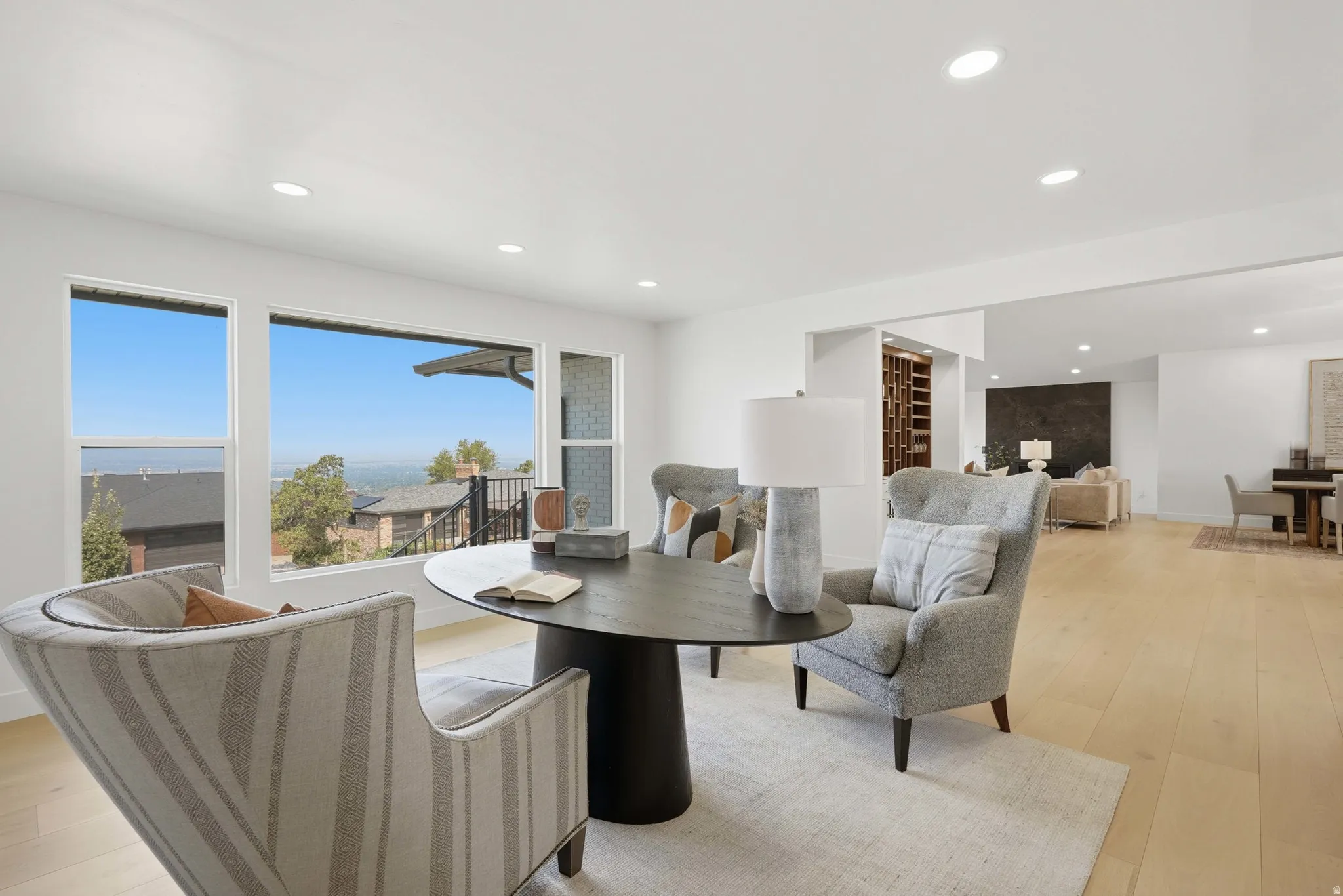 Large windows with mountain backdrop, light wood-finish flooring, recessed lighting, built-in shelving, and open-concept design