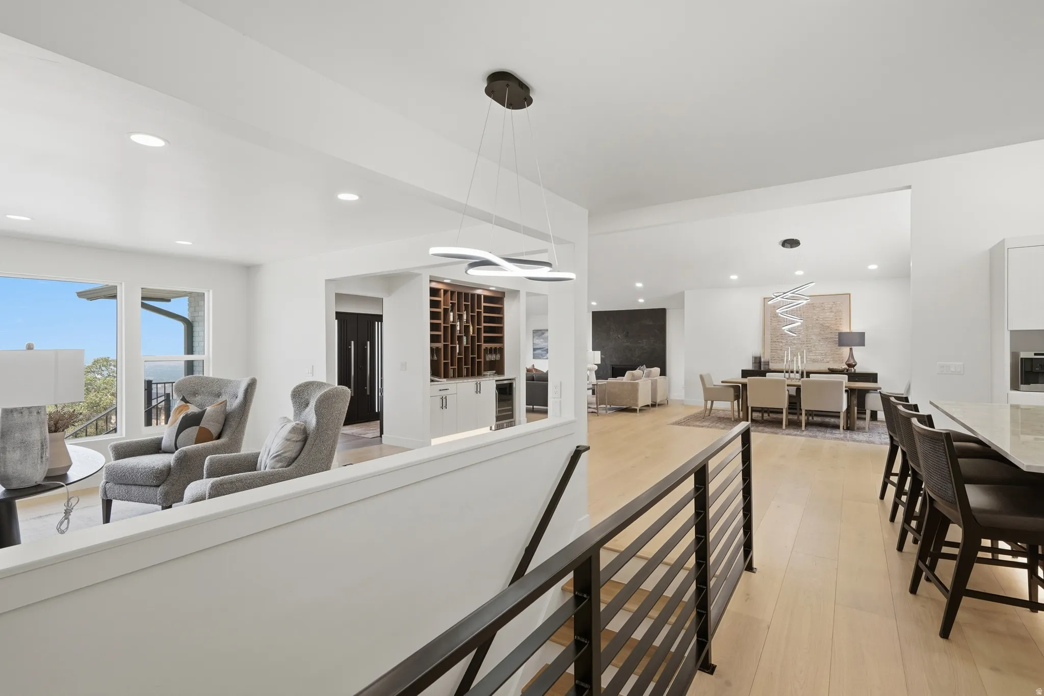 Open-concept living space with light wood-finish flooring, recessed lighting, and a modern horizontal bar railing
