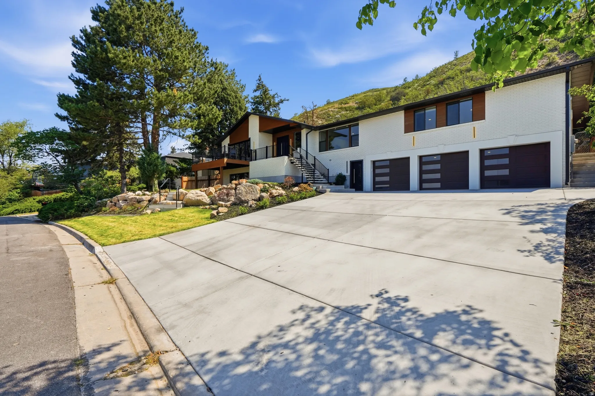 White exterior with dark trim and a large concrete driveway