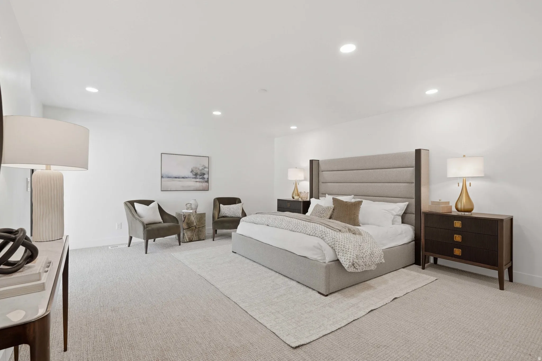 Recessed lighting, light-toned carpeting, ample wall space, and a padded headboard