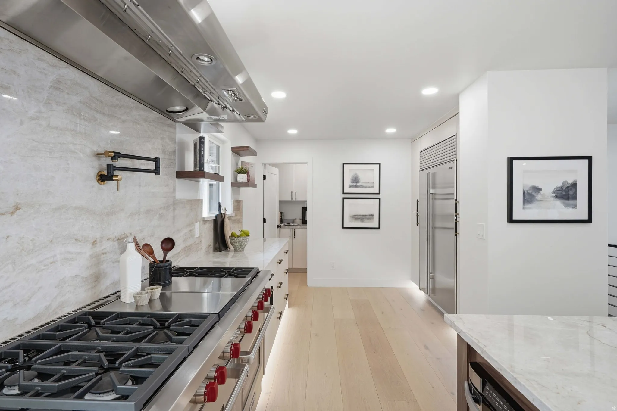 Kitchen featuring a professional-grade gas range with a stainless steel vent hood, a full-height stone backsplash, a pot filler, and recessed lighting