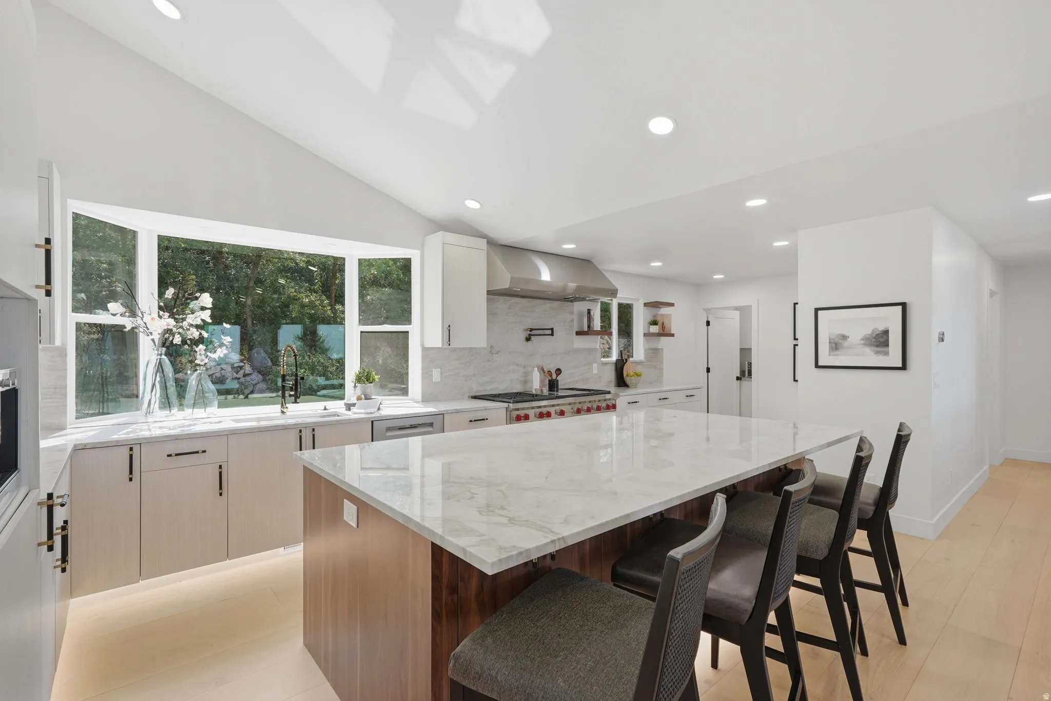 Expansive kitchen island with a stone countertop, bay window, vaulted ceiling, recessed lighting, and wood-finish flooring