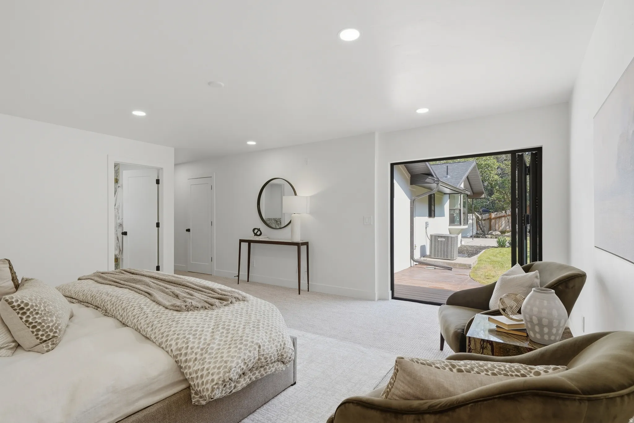 Recessed lighting throughout, carpeted flooring, and a folding glass door leading to an exterior patio