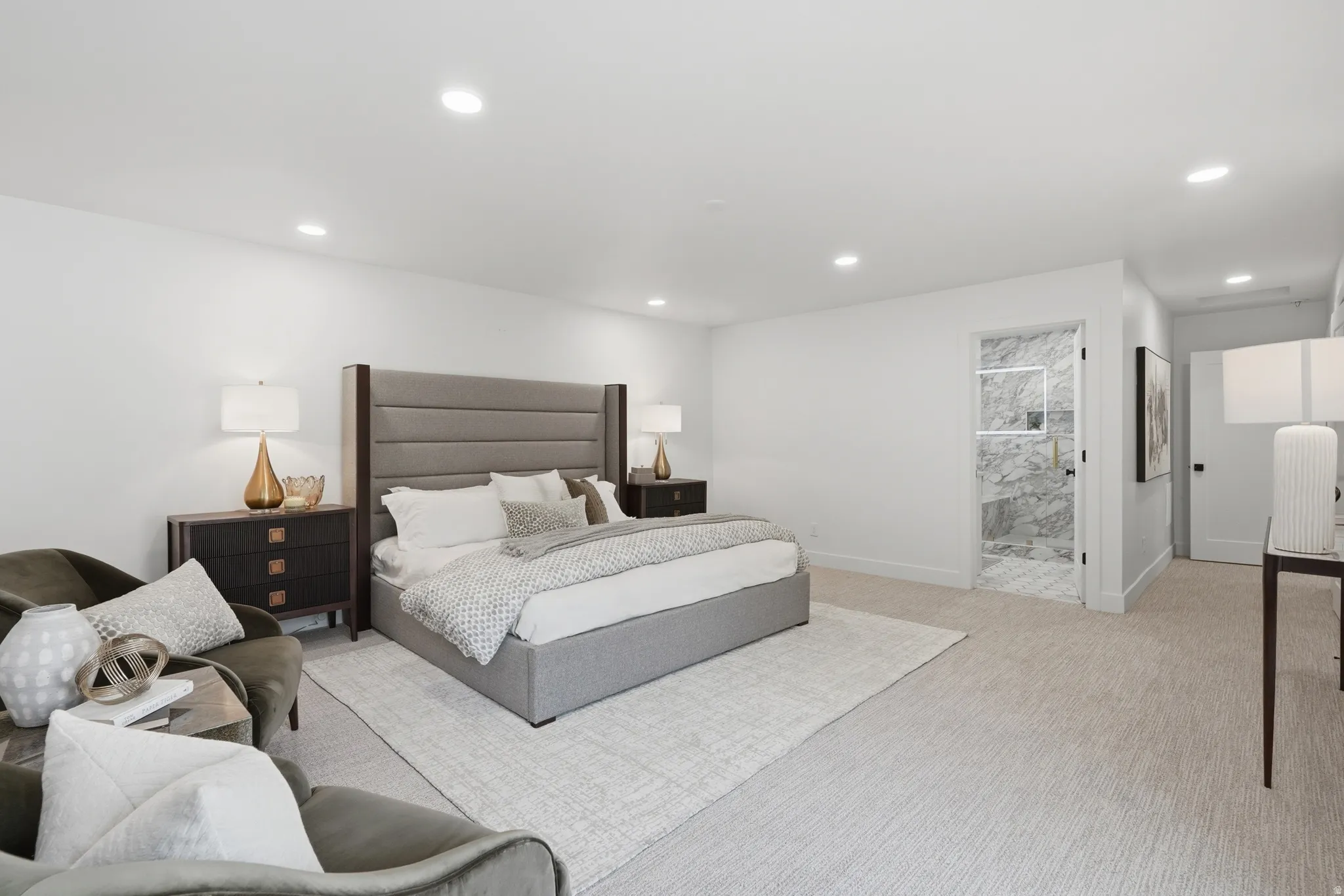 Recessed lighting, light-toned carpeting, a built-in shower with marble-look wall tiles, and a glass shower door