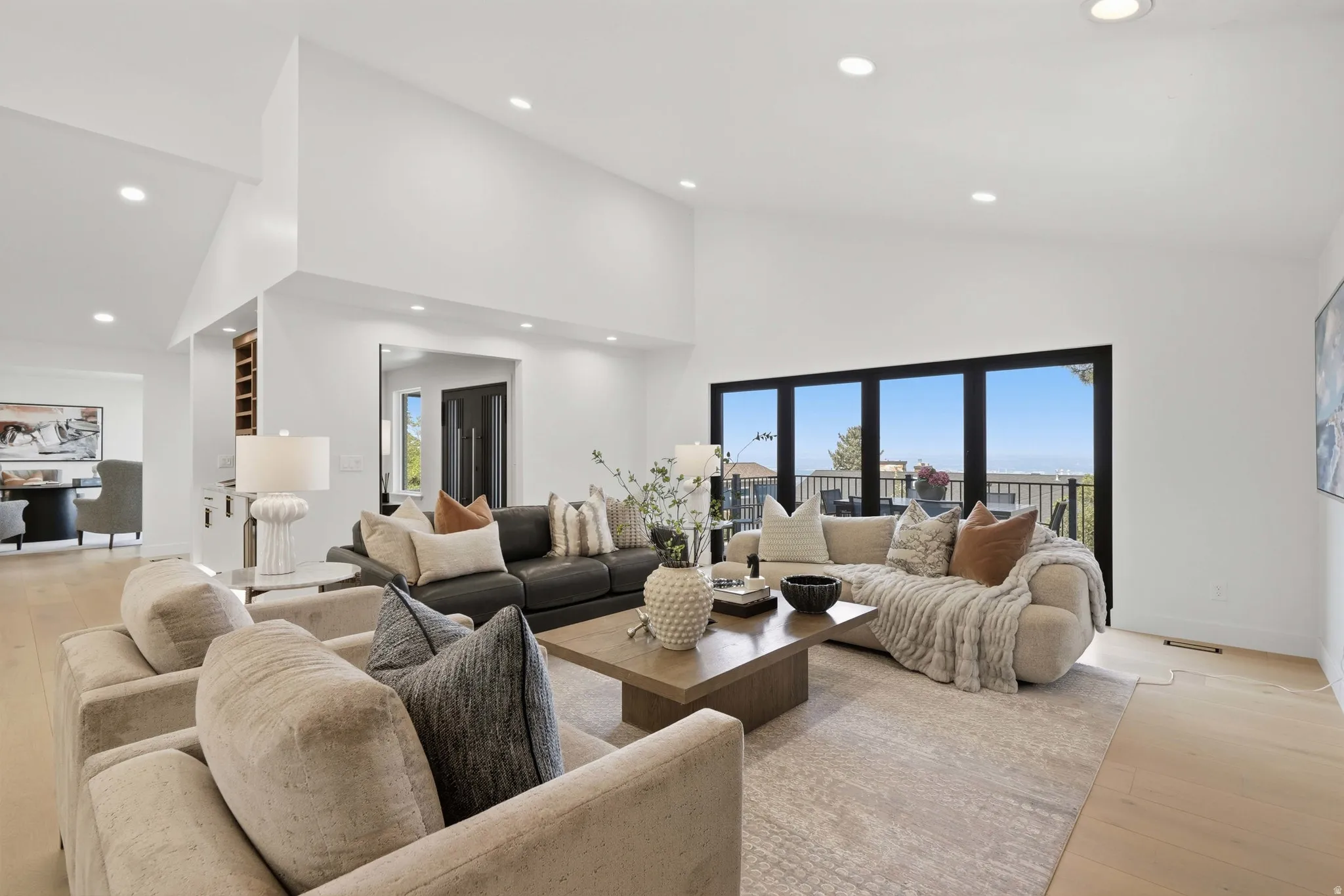 Vaulted ceilings with recessed lighting, expansive glass doors, wood-finish flooring, and built-in shelving