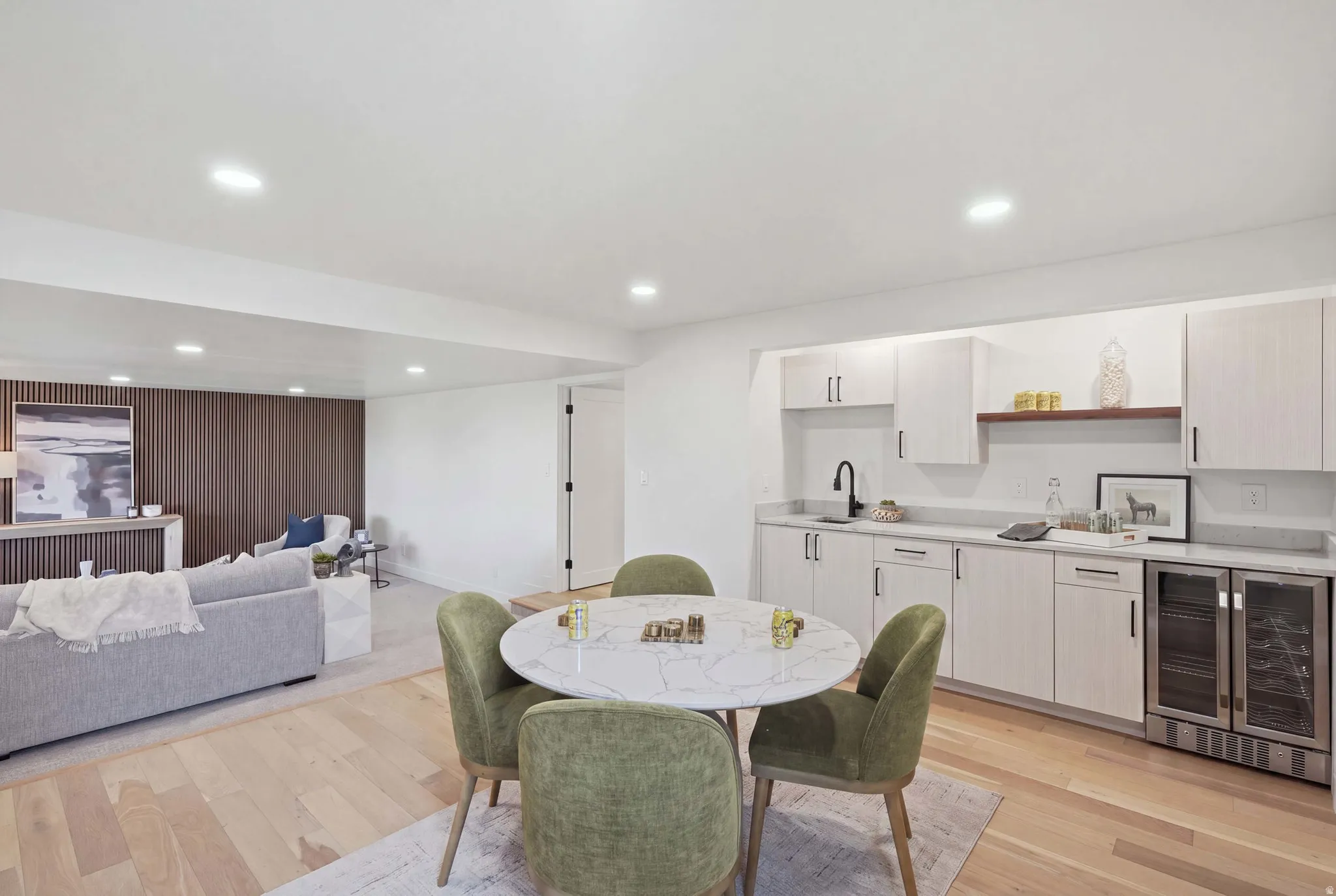 Recessed lighting, wood-finish flooring, wood slatted accent wall, built-in cabinetry, and integrated beverage refrigerators