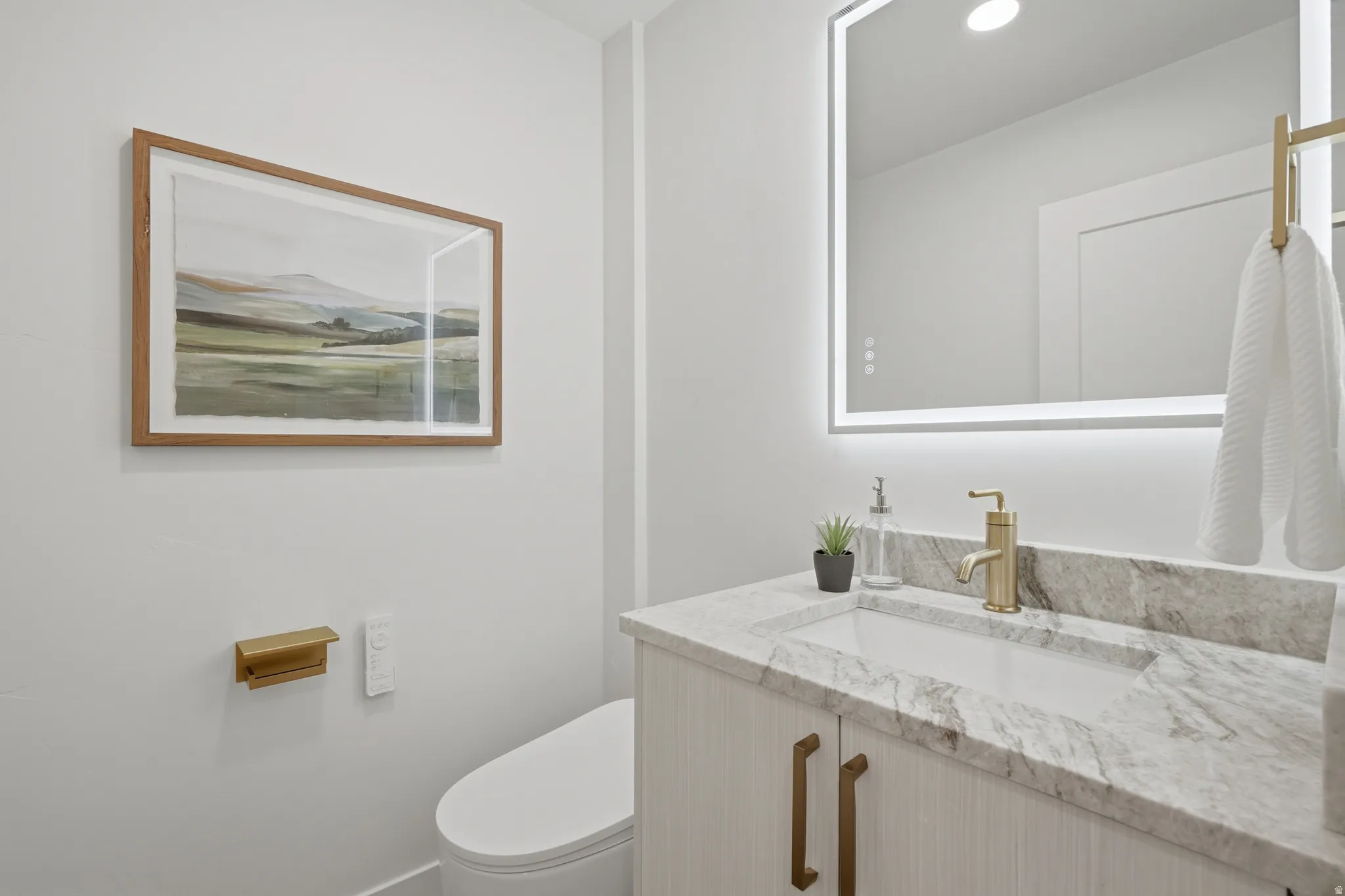Vanity with integrated rectangular sink, light-toned countertop, and gold-finish hardware