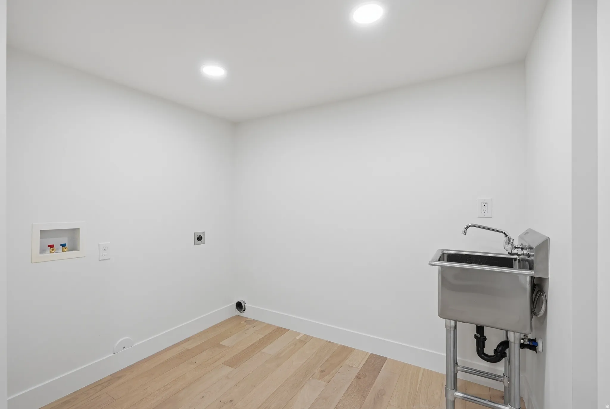 Laundry area featuring a utility sink with a chrome faucet, wood-finish flooring, and recessed lighting
