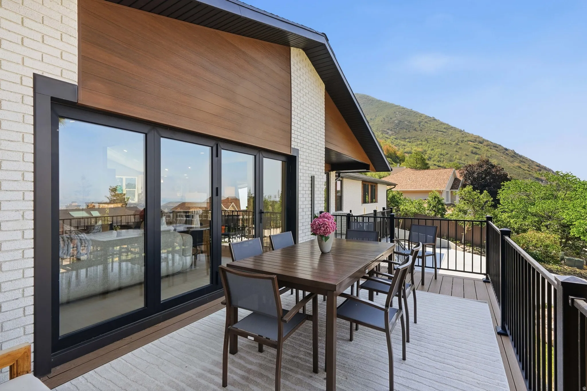 Expansive exterior deck featuring a composite surface, black metal railings, and a wood-paneled overhang