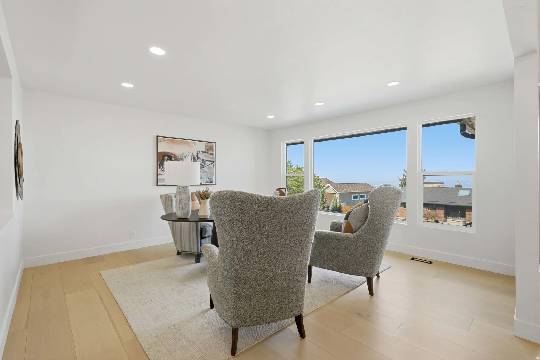 Expansive windows with surrounding scenery, wood-finish flooring, recessed lighting, and crisp white walls