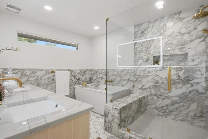 Recessed lighting, large soaking tub, glass-enclosed shower, integrated shower niches, and gold-tone fixtures