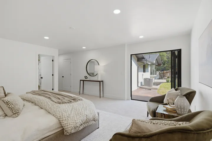 Recessed lighting throughout, carpeted flooring, and a folding glass door leading to an exterior patio