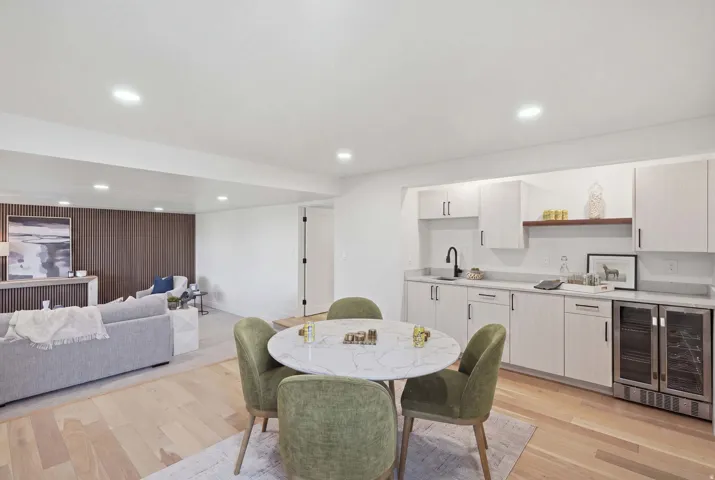 Recessed lighting, wood-finish flooring, wood slatted accent wall, built-in cabinetry, and integrated beverage refrigerators