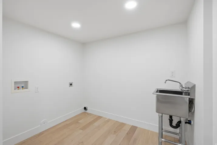 Laundry area featuring a utility sink with a chrome faucet, wood-finish flooring, and recessed lighting