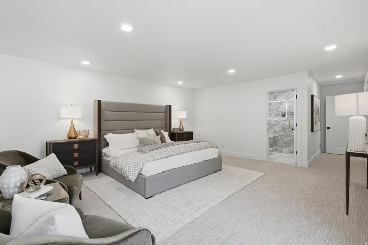 Recessed lighting, light-toned carpeting, a built-in shower with marble-look wall tiles, and a glass shower door