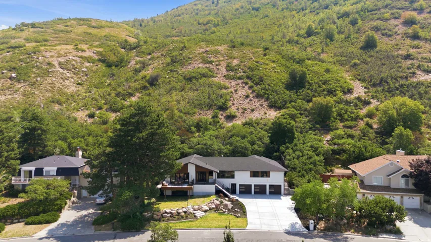 Modern exterior, three-car garage, large driveway, terraced landscaping, mountain backdrop
