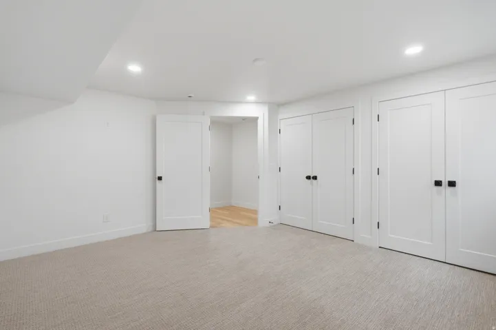 Recessed lighting, light-toned carpeting, white walls, multiple built-in storage closets, and an entryway with wood-finish flooring