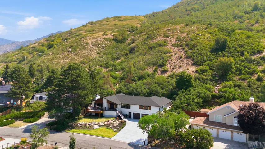 Contemporary residence with a black roof, white exterior, and a prominent hillside backdrop