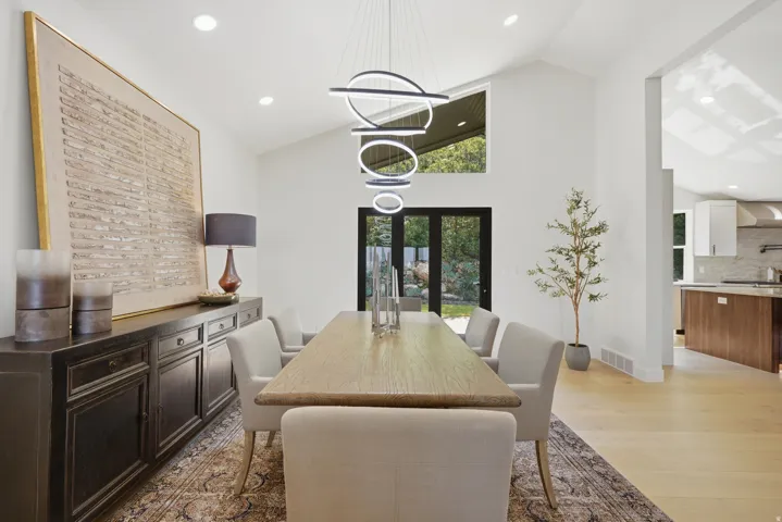 Vaulted ceilings, contemporary pendant lighting, wood-finish flooring, recessed lighting, and black-framed French doors