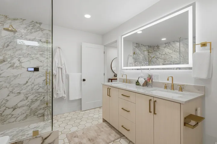 Walk-in shower with full height stone-finish tiling and glass enclosure