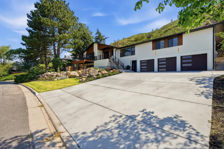 White exterior with dark trim and a large concrete driveway