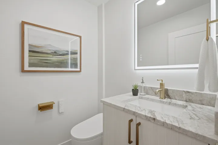 Vanity with integrated rectangular sink, light-toned countertop, and gold-finish hardware