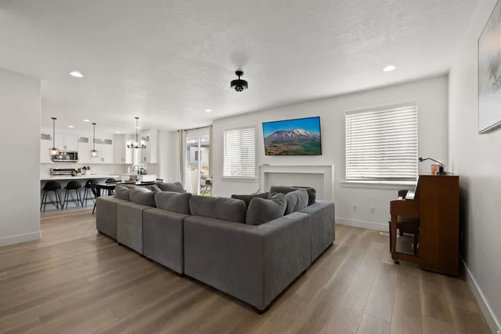 Open-concept living area featuring wood-finish flooring, recessed lighting, and a white fireplace surround