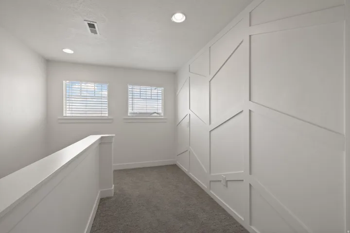Geometric accent wall, recessed lighting, carpet flooring, dual windows, and white trim