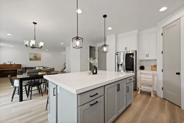 Kitchen island featuring a light-toned countertop, gray cabinetry, and pendant lighting