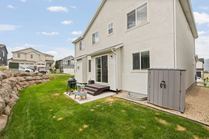 Private backyard with a concrete patio, wood-finish stairs, and a rock retaining wall
