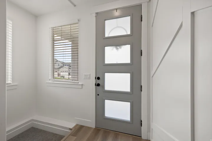 Light wood-finish flooring with a modern paneled entry door
