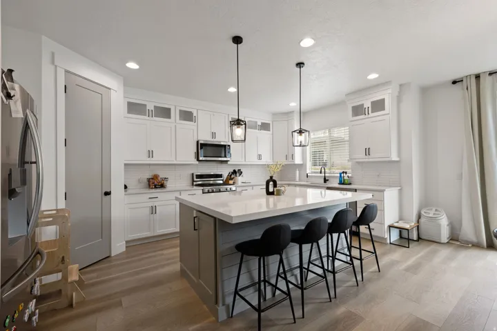 Kitchen featuring an expansive center island with seating, white shaker cabinetry, white subway tile backsplash, and wood-finish flooring