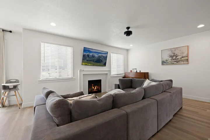 Living space featuring light wood-finish flooring, recessed lighting, and a white fireplace with a mantel