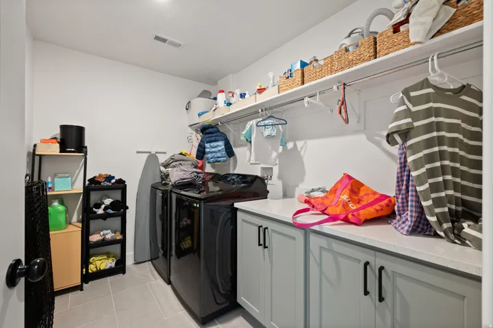 Integrated laundry room with built-in cabinetry, solid surface countertop, and upper shelving