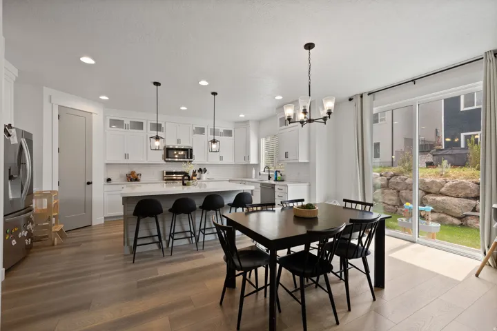 Spacious kitchen featuring white cabinetry, a large island with counter seating, stainless steel appliances, and wood-finish flooring
