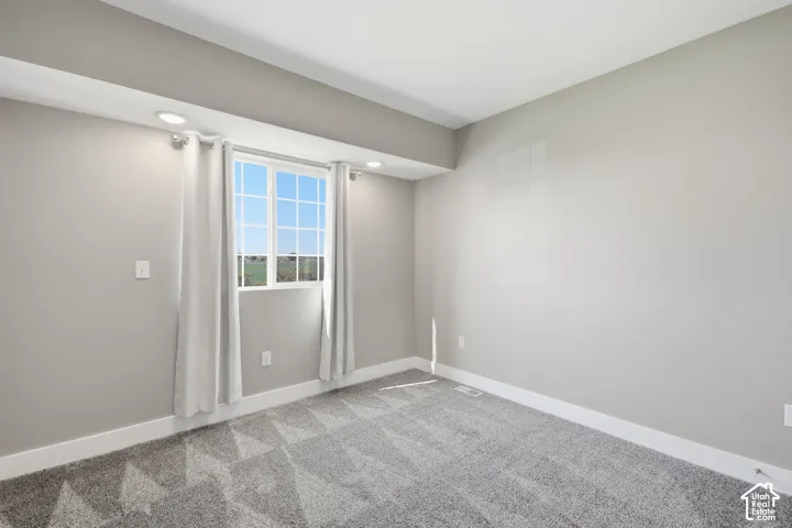 Recessed ceiling lighting, a window with grid panes, textured carpeting, neutral wall tones, and white trim