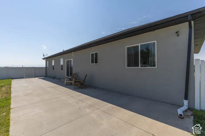 Expansive concrete patio with stucco exterior, sliding glass door, and multiple windows