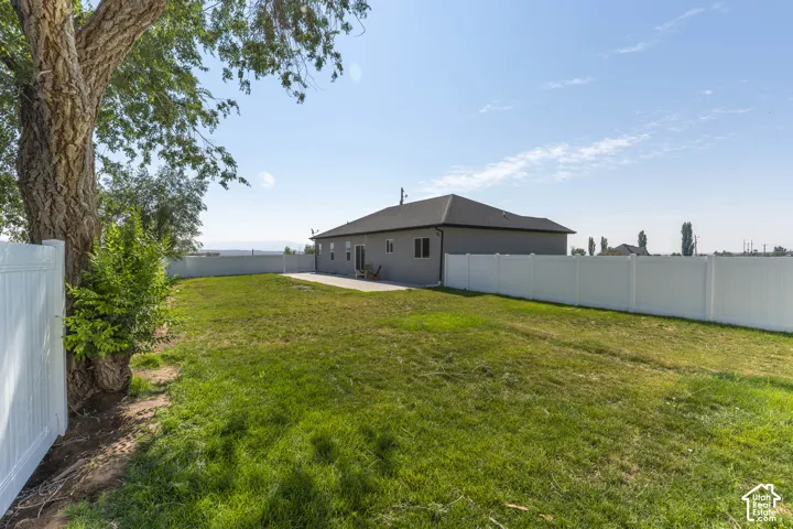 Expansive backyard featuring a manicured lawn, concrete patio, and full perimeter fencing