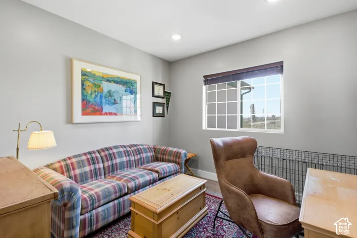 Recessed lighting, light gray wall finishes, wood-finish flooring, and a large window with blind