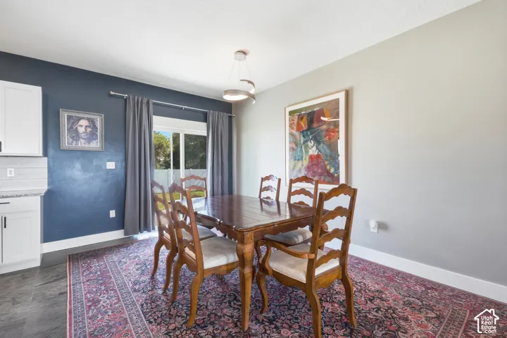 Sliding glass door, contemporary ceiling light fixture, white cabinetry, light countertops, wood-finish flooring