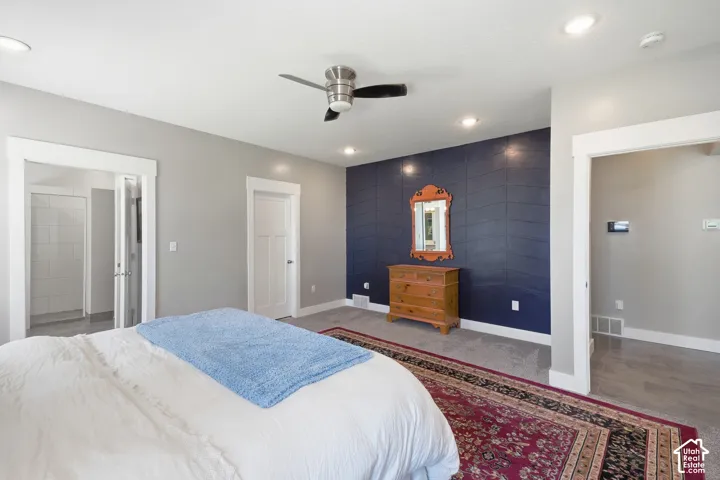 Recessed ceiling lighting, ceiling fan, carpet flooring, accent wall, and an open doorway leading to a tiled shower